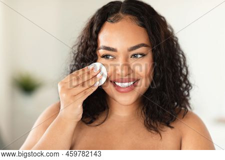 Closeup Portrait Of Black Plus Size Woman Using Cotton Pad, Erasing Make Up From Her Face, Applying 