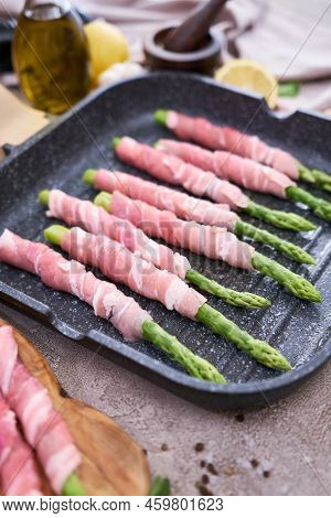 Cooking Aspargus Covered With Bacon On A Grill Frying Pan