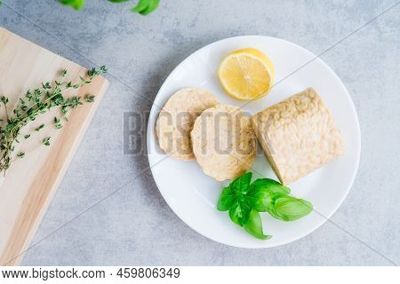 Top View Raw Tempeh Or Tempeh, Made Of Fermented Soybean Seeds. Tempeh Slices On Plate With Herbs. S