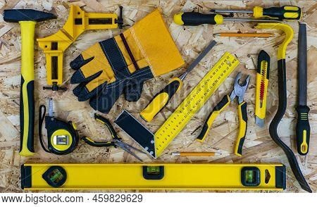 Construction Tools Arranged On A Osb Construction Plate Background. All Tools With Yellow Elements. 