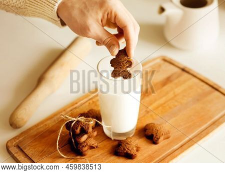 On A Table On A Kitchen Board There Is A Glass Of Milk And Oatmeal Homemade Cookies, And A Man Dips 