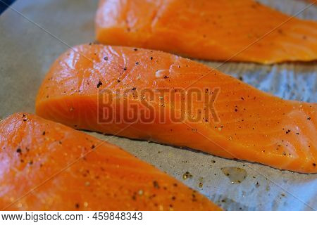 Fresh Raw Salmon Fish Fillet Steak Pieces With Salt And Pepper On The Baking Paper Sheet Ready To Ba
