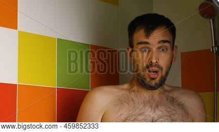 A Man Turns On The Cold Water In The Shower And Squirms His Face From The Cold. Caucasian Man Takes 