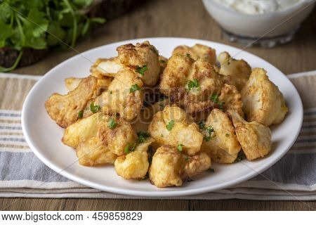 Fried In Batter Cauliflower Florets Served On A Black Plate On A Grey Concrete Table With Ingredient