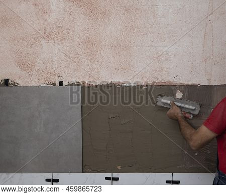 Laying Wall Ceramic Tile. Renovating The Wall. Construction Worker Laying Tile Over Concrete Wall Us