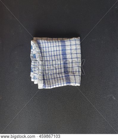 Folded White Blue Plaid Napkin On Black Board Table.