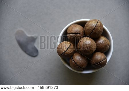 Macadamia Nut In A Dish With A Bottle Opener On A Gray Background. Macadamia Nut Prepared For Use In
