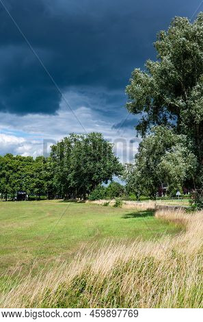 Zwolle, Overijssel, The Netherlands, 07 15 2022 - Grass, Trees And Dark Blue Clouds At The Nature Re