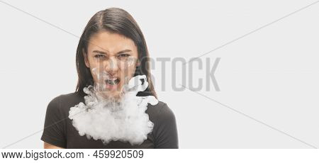 Angry Young Girl With Dark Hair Releases Smoke From The Mouth Isolated Over White Background. Concep