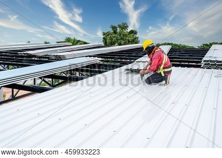 A Roofer Construction Worker Install New Roof, Electric Drill Used On New Roofs With White Metal She