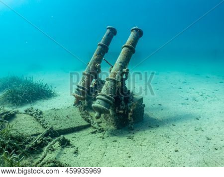 Antique Cannons On A Sandy Sea Floor. Beautiful Turquoise Water In The Background