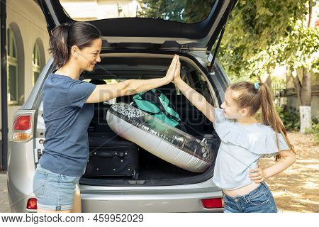 Woman And Small Girl Doing Highfive Before Leaving On Holiday Trip At Seaside, Loading Baggage And I