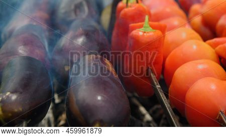 Close-up Of Fresh Vegetables Being Grilled. Eggplant, Peppers And Tomatoes On Skewers Roasted On Cha