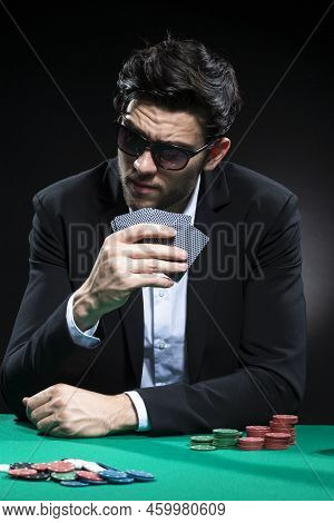 Caucasian Brunet Pocker Player At Pocker Table With Chips And Cards While Thoughfully Sitting
