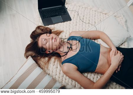 Adult Mature Woman Doing Yoga Nidra And Lays At Home With Online Tutorials On Laptop