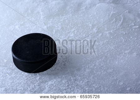 Black hockey puck on ice rink background