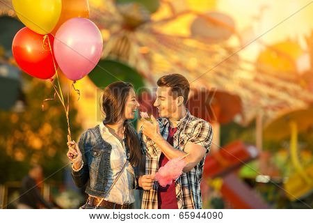Happy young  couple eating cotton candy in amusement park