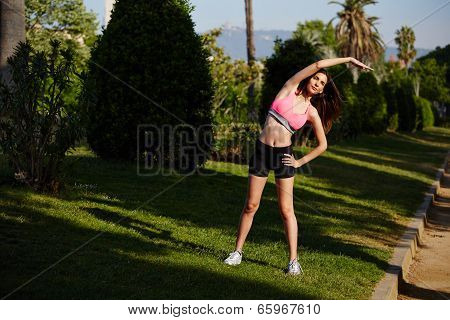 Beautiful female runner doing stretching and exercise before jogging in the park