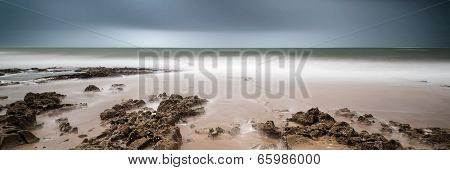 Landscape Panorama Long Exposure Image Of Rocks And Sandy Beach