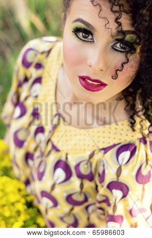 young smiling girl in a sunny summer day with curls and beautiful makeup looks at the sky