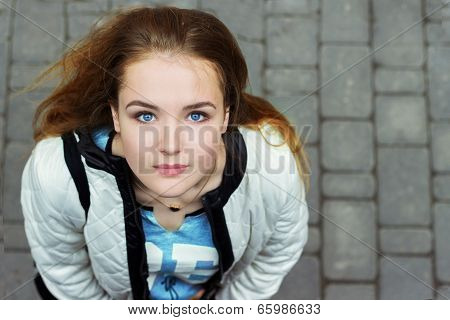 young beautiful girl with blue eyes and red hair walking in the streets