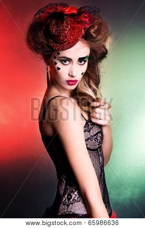 young attractive woman with beautiful makeup in green and red colors in the red hat at the masquerad