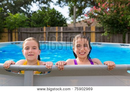 kid girls swimming in the pool in backyard happy