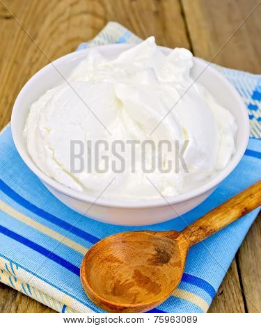 Yogurt in white bowl with spoon on board