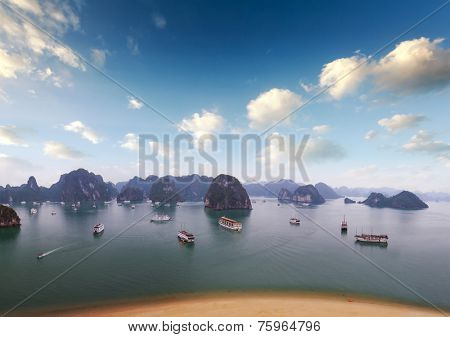 Halong Bay Vietnam. Boats, junks and tourist ships cruise. Holiday vacation destination background. Sandy beach, islands and blue sky with clouds