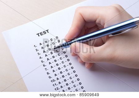 Close Up Of Hand Filling Test Score Sheet With Answers