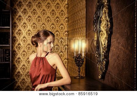 Romantic young woman in evening dress posing in vintage interior. Classic luxurious interior. Fashion shot.