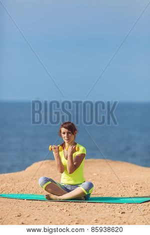 A young woman fitness trainer, shows a set of exercises with dumbbells.