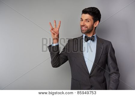 Smiling man showing three fingers and looking at camera