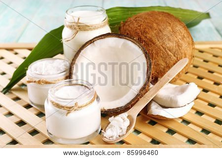 Fresh coconut oil in glassware on color wooden table and grid tray background