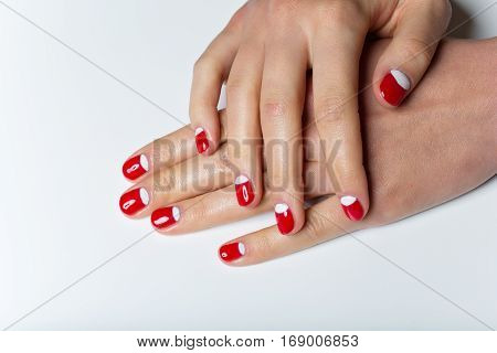 Close-up shot of young femle hands with red and white nail manicure. Copy space.