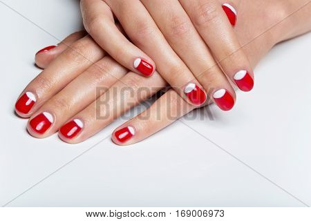 Close-up shot of young femle hands with red and white nail manicure. Copy space.