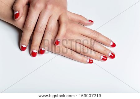 Close-up shot of young femle hands with red and white nail manicure. Copy space.