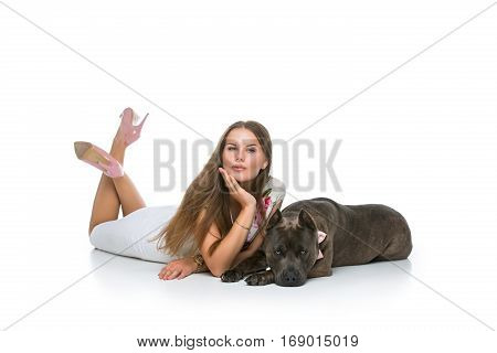 Beautiful elegant happy young woman in white dress hugging adult grey amstafford terrier dog with bow on neck. Isolated on white background. Copy space.