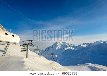 Ski lift station in mountains at winter. Alpine winter mountain landscape. French Alps covered with snow in sunny day. Val-d'Isere, Alps, France