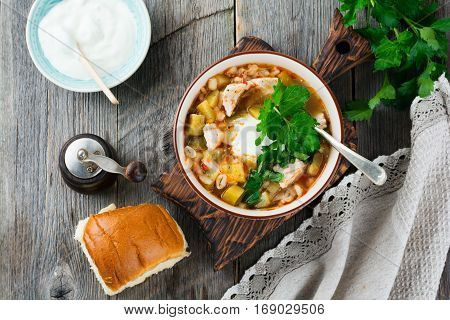 Traditional Russian soup-Rassolnik with pickled cucumber barley chicken tomatoes and parsley in ceramic bowl. Selective focus. Top view.