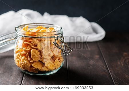 Close up of cornflackes in jar on dark wooden background selective focus. Space for text.