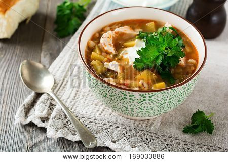 Traditional Russian soup-Rassolnik wit hpickled cucumber barley chicken tomatoes and parsley in ceramic bowl. Selective focus.