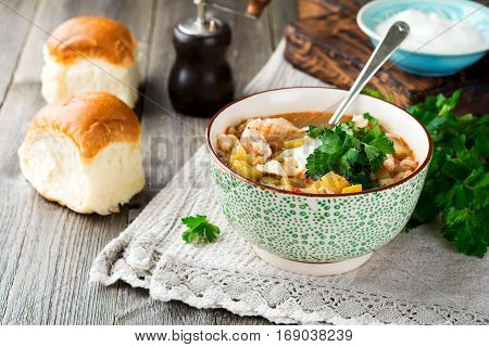 Traditional Russian soup-Rassolnik wit hpickled cucumber barley chicken tomatoes and parsley in ceramic bowl. Selective focus.