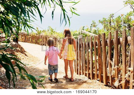 Two kids walking dowm the small path, back view, image taken in Capo Vaticano, Calabria, Italy