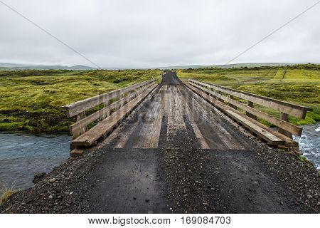 wooden bridge across the wild icelandic river Iceland view at Iceland green plains during summertime