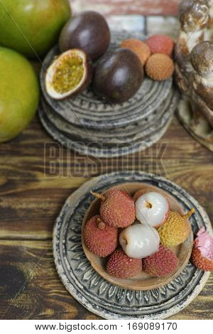 Tropical fruits - Lychees and Passion Fruit or Maracuya and Mango on wooden background