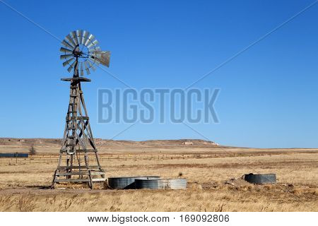 An agriculture farming windmill on the eastern plains of Colorado with the hills of the Pawnee Buttes Grasslands in the background