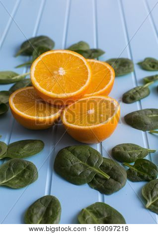 Slices of orange and green leaves on a blue background. Vegetarin. Raw food diet