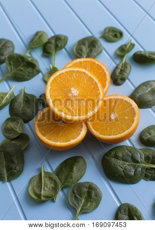 Slices of orange and green leaves on a blue background. Vegetarin. Raw food diet