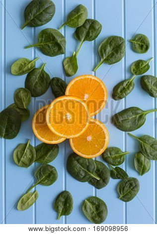 Slices of orange and green leaves on a blue background. Vegetarin. Raw food diet